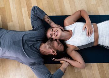Attain on 5th apartment homes with A smiling woman lies on a yoga mat as a man rests beside her, holding her face and hand affectionately.