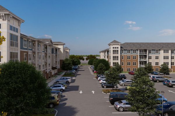 Attain on 5th apartment homes with A parking lot with cars parked between two four-story apartment buildings on a sunny day.